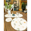 Round floral placemats on a wooden table with decorative items. Daisy Blossom Braided Table Linens - Three Styles available at Quilted Cabin Home Decor.