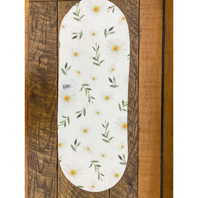 Oval-shaped table runner with floral pattern on a wooden background. Daisy Blossom Braided Table Linens - Three Styles available at Quilted Cabin Home Decor.