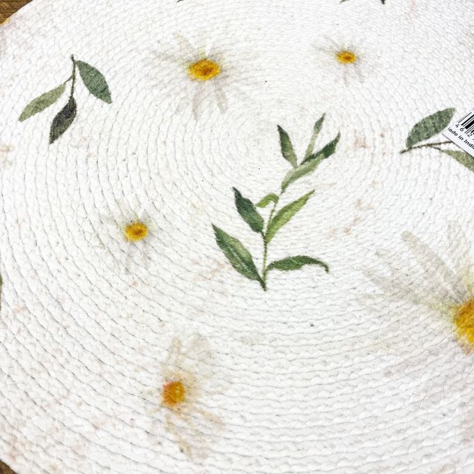 Round woven mat with floral patterns on a white background. Daisy Blossom Braided Table Linens - Three Styles available at Quilted Cabin Home Decor.