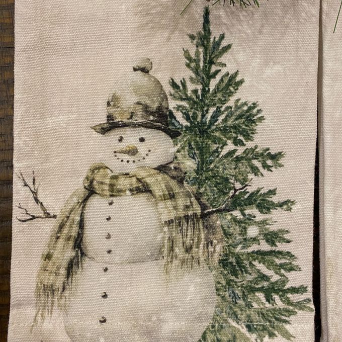 Decorative tea towel with a snowman and Christmas tree design on a textured background. Christmas Tea Towels - Two Styles