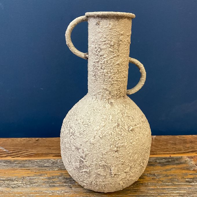 Textured ceramic vase with handles on a wooden surface against a blue wall. Rustic Metal Vases - Two Colours available at Quilted Cabin Home Decor.