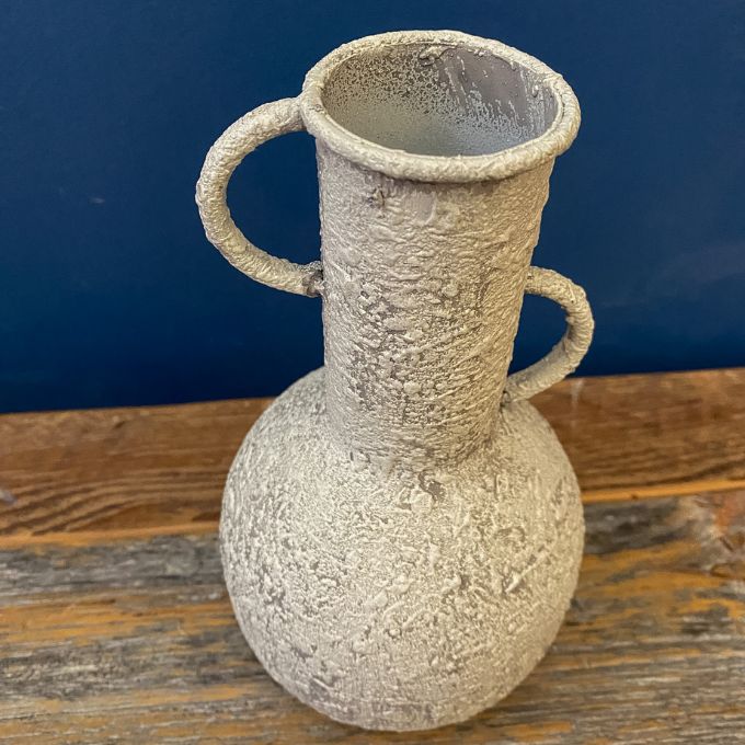 Textured ceramic vase with handles on a wooden surface against a blue background. Rustic Metal Vases - Two Colours available at Quilted Cabin Home Decor.