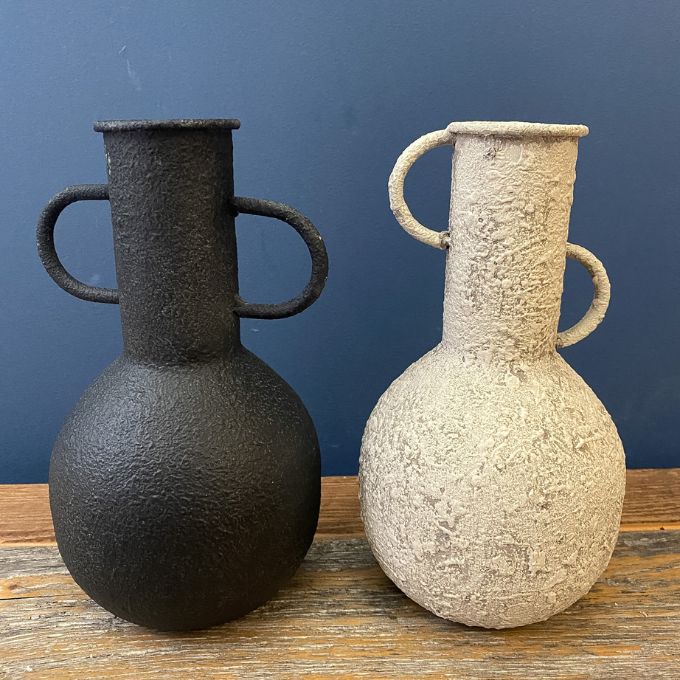 Two textured vases, one black and one white on a wooden surface with a blue background. Rustic Metal Vases - Two Colours available at Quilted Cabin Home Decor.