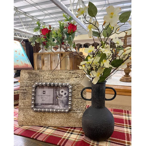 Decorative setup with a glittery photo frame, black vase with flowers, and plaid tablecloth. Rustic Metal Vases - Two Colours available at Quilted Cabin Home Decor.