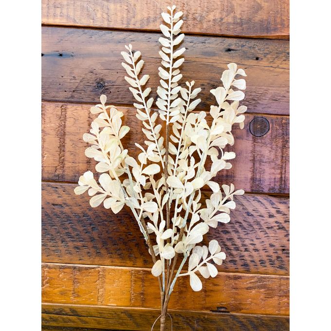 Artificial white leaf branch against a wooden background. Tan Leaf Stem Spray available at Quilted Cabin Home Decor.