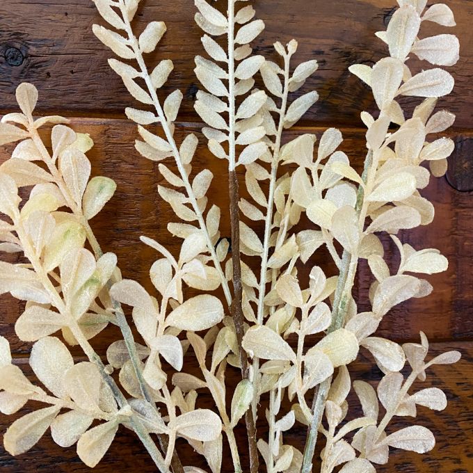 Artificial leaf branches on a wooden surface. Tan Leaf Stem Spray available at Quilted Cabin Home Decor.