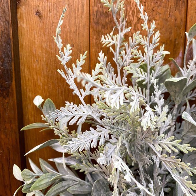Frosty artificial plant against a wooden background. Fern Spray available at Quilted Cabin Home Decor.