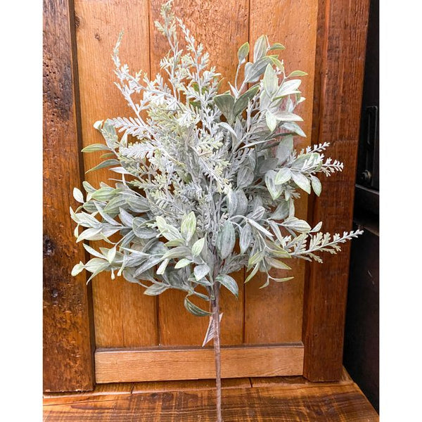 Artificial greenery arrangement on a wooden surface with a wooden panel background. Fern Spray available at Quilted Cabin Home Decor.