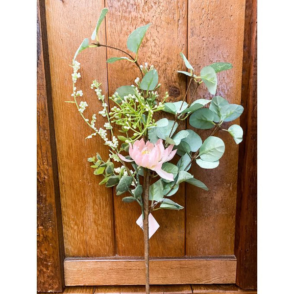 Artificial plant with pink flower and green leaves against a wooden background. Purely Spring Pink Mum Floral Spray available at Quilted Cabin Home Decor.