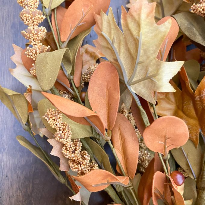 Close-up of artificial leaves and berries with a blurred background. Maple Leaf and Walking Fern Floral Spray available at Quilted Cabin Home Decor.
