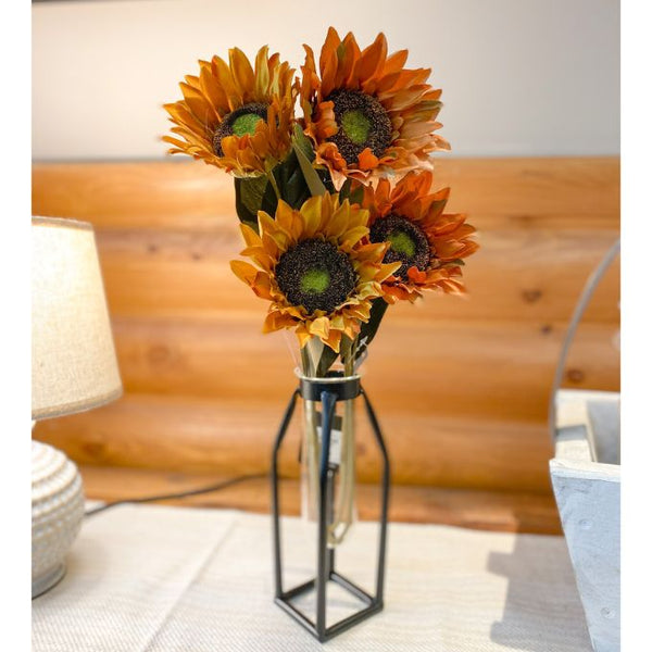 Bouquet of sunflowers in a glass vase on a table with a wooden wall background. Sunflower Sprays - Two Colours available at Quilted Cabin Home Decor.