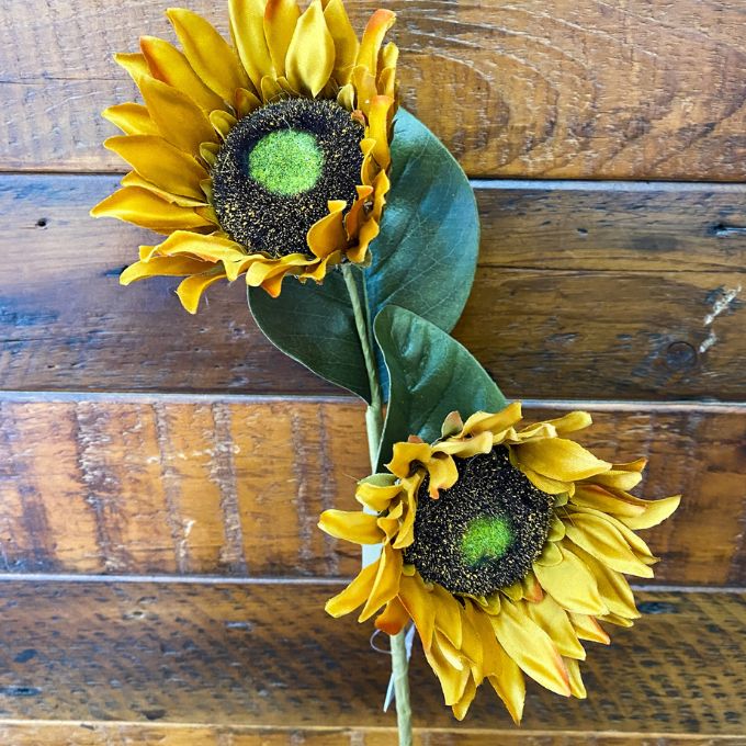 Two sunflowers on a wooden surface. Sunflower Sprays - Two Colours available at Quilted Cabin Home Decor.