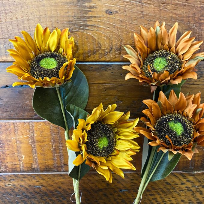 Four artificial sunflowers on a wooden surface. Sunflower Sprays - Two Colours available at Quilted Cabin Home Decor.