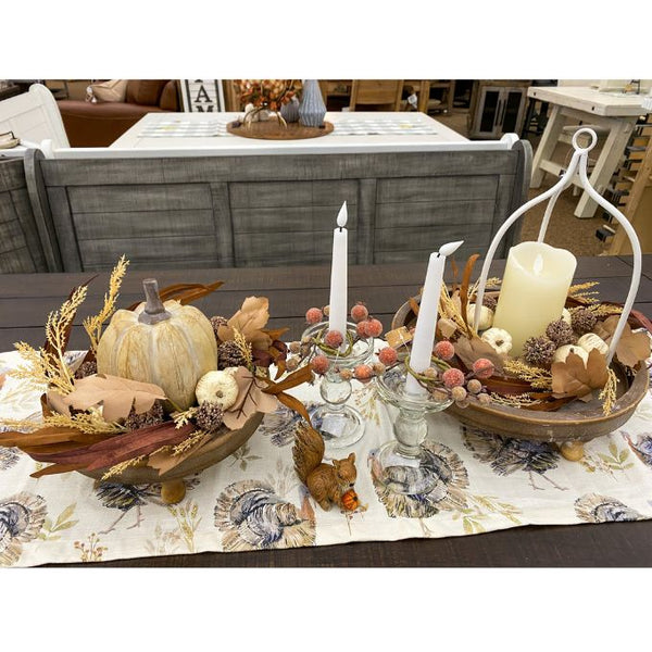 Decorative table setting with candles, pumpkins, and fall-themed decor on a floral tablecloth. Pumpkin and Oak Leaf Candle Ring and Floral Spray available at Quilted Cabin Home Decor.