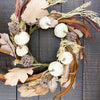 Decorative wreath with white pumpkins, dried leaves, and flowers on a wooden background. Pumpkin and Oak Leaf Candle Ring and Floral Spray available at Quilted Cabin Home Decor.