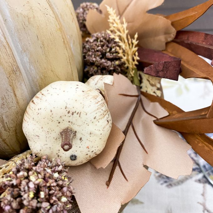 Decorative arrangement with pumpkins and flowers in neutral colors. Pumpkin and Oak Leaf Candle Ring and Floral Spray available at Quilted Cabin Home Decor.