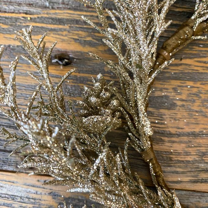 Gold glittery branches of a candle ring on a wooden surface. Golden Candle Ring/Small Wreath available at Quilted Cabin Home Decor.