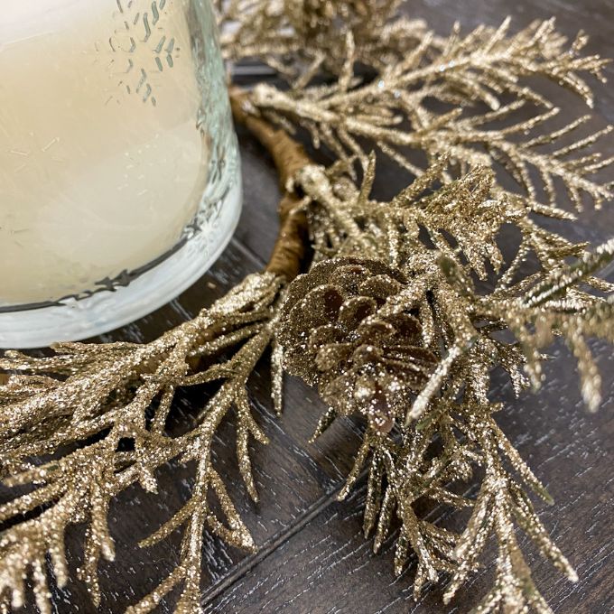Gold glittery candle ring next to a candle on a dark surface. Golden Candle Ring/Small Wreath available at Quilted Cabin Home Decor.