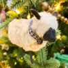 Plush sheep ornament hanging on a decorated Christmas tree. Wooly Sheep Ornament available at Quilted Cabin Home Decor.