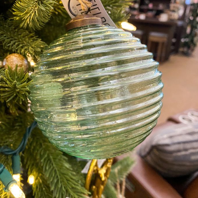 Green ribbed glass ornament on a Christmas tree with blurred indoor background. Vintage Green Glass Ornaments - Three Styles available at Quilted Cabin Home Decor.