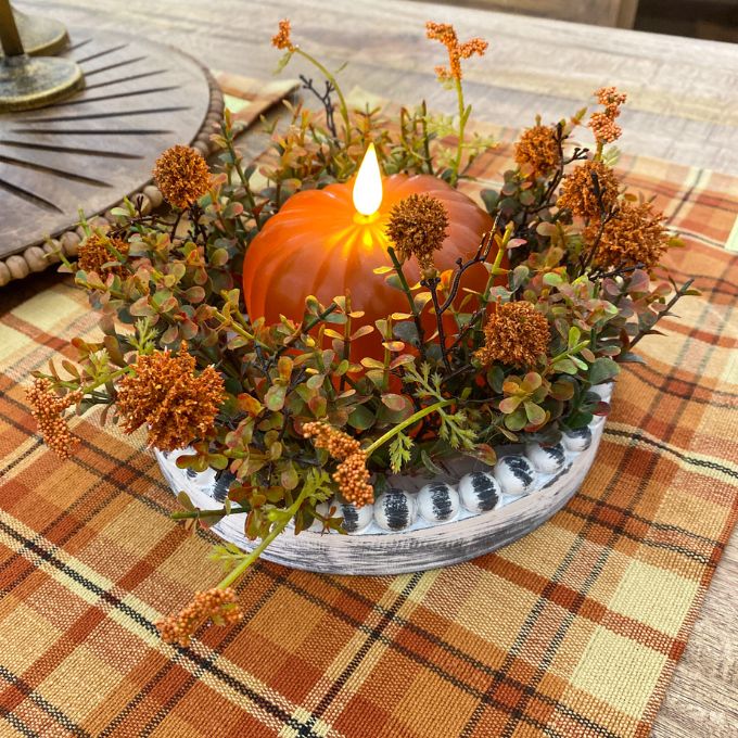 Decorative fall arrangement with a candle and orange LED pumpkin candle on a plaid tablecloth. Orange LED Pumpkin Candle available at Quilted Cabin Home Decor.