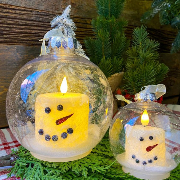 Two sizes of a snowman LED Candle in a clear plastic ornament. Available at Quilted Cabin Home Decor.