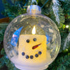 Two sizes of a snowman LED Candle in a clear plastic ornament. Available at Quilted Cabin Home Decor.