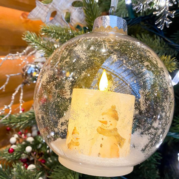 Decorative Christmas ornament with a candle and snowman inside, on a tree. Ball Ornaments with LED Candles - Three Styles available at Quilted Cabin Home Decor.
