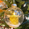 Decorative Christmas ornament with a candle inside a clear glass ball on a tree. Ball Ornaments with LED Candles - Three Styles available at Quilted Cabin Home Decor.