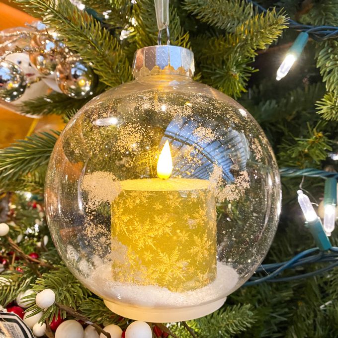 Decorative Christmas ornament with a candle inside a clear glass ball on a tree. Ball Ornaments with LED Candles - Three Styles available at Quilted Cabin Home Decor.