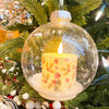 Decorative Christmas ornament with a lit candle inside a clear glass ball, hanging on a tree. Ball Ornaments with LED Candles - Three Styles available at Quilted Cabin Home Decor.