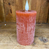 Textured orange candle with a white wick on a wooden surface. Orange Ridged LED 4" Votive Candle available at Quilted Cabin Home Decor.