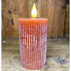 Textured orange candle with a lit flame on a wooden surface. Orange Ridged LED 4" Votive Candle available at Quilted Cabin Home Decor.