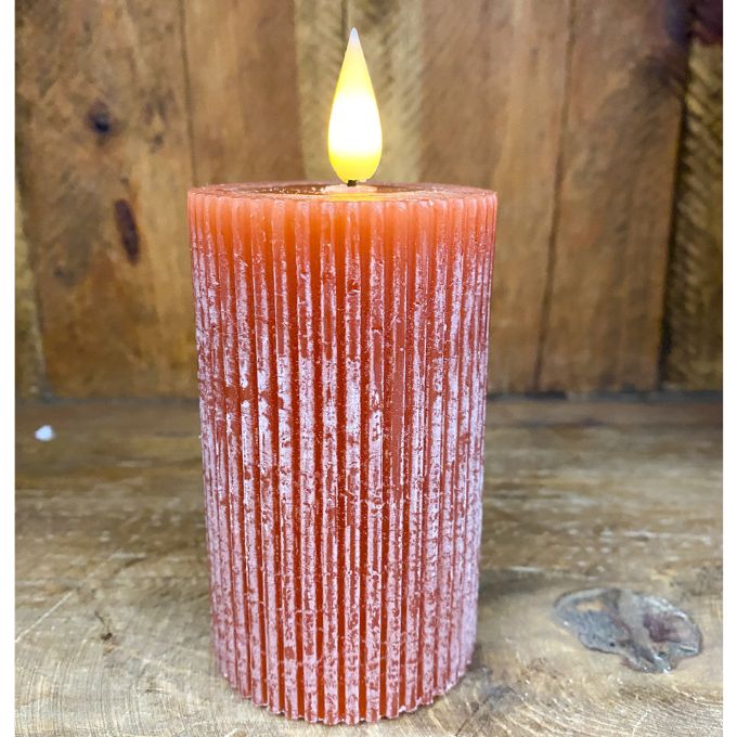 Textured orange candle with a lit flame on a wooden surface. Orange Ridged LED 4" Votive Candle available at Quilted Cabin Home Decor.