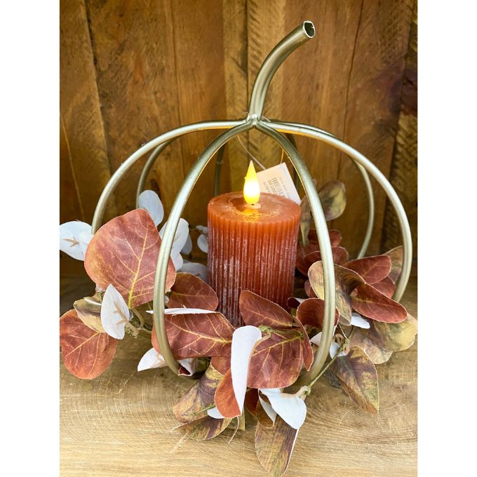 Decorative candle holder with a lit orange candle. Orange Ridged LED 4" Votive Candle available at Quilted Cabin Home Decor.