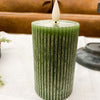 Green textured candle with a white wick on a white surface. Green Ridged LED 4" Votive Candle available at Quilted Cabin Home Decor.