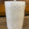 White candle with snowflake patterns on a wooden surface.  White Snowflake LED 5" Pillar Candle available at Quilted Cabin Home Decor.