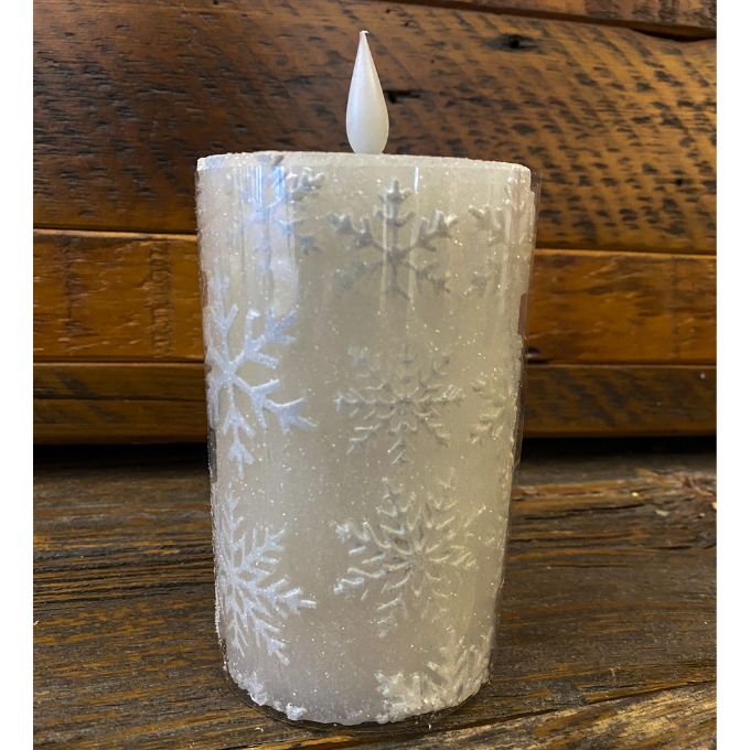 Frosted candle with snowflake patterns on a wooden surface.  White Snowflake LED 5" Pillar Candle available at Quilted Cabin Home Decor.