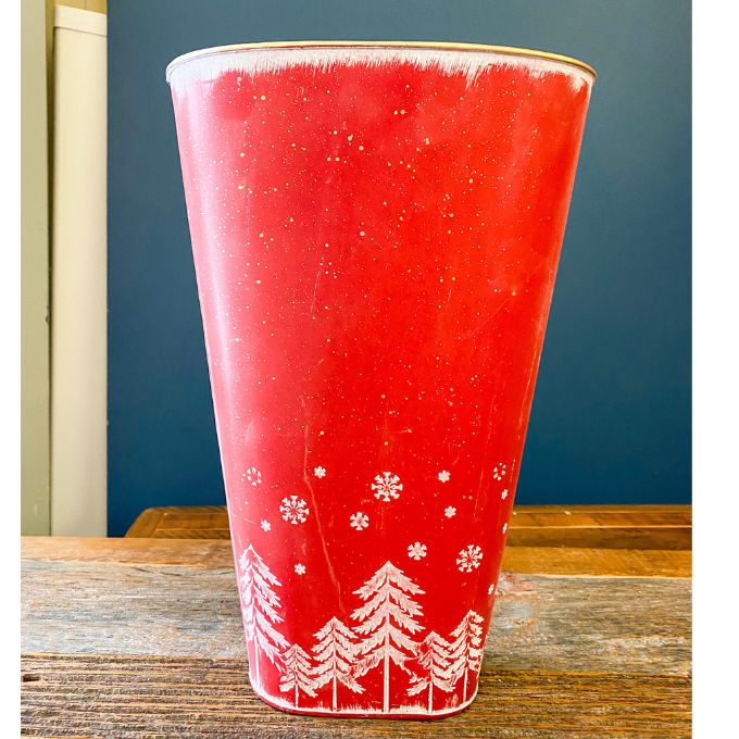 Red & White Tree Wall Bucket is a tall red metal bucket with white christmas trees and snowflakes along the bottom of it. Available at Quilted Cabin Home Decor.