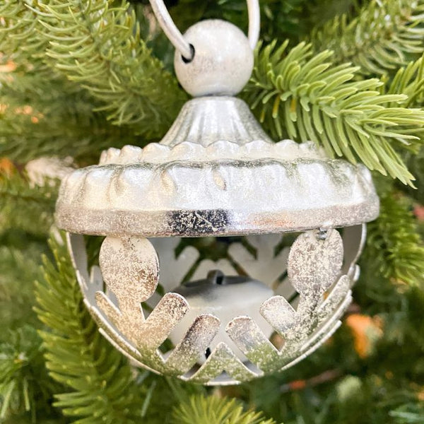 Decorative silver ornament with snowflake cutouts on a Christmas tree. Silver Snowflake Ornament available at Quilted Cabin Home Decor.