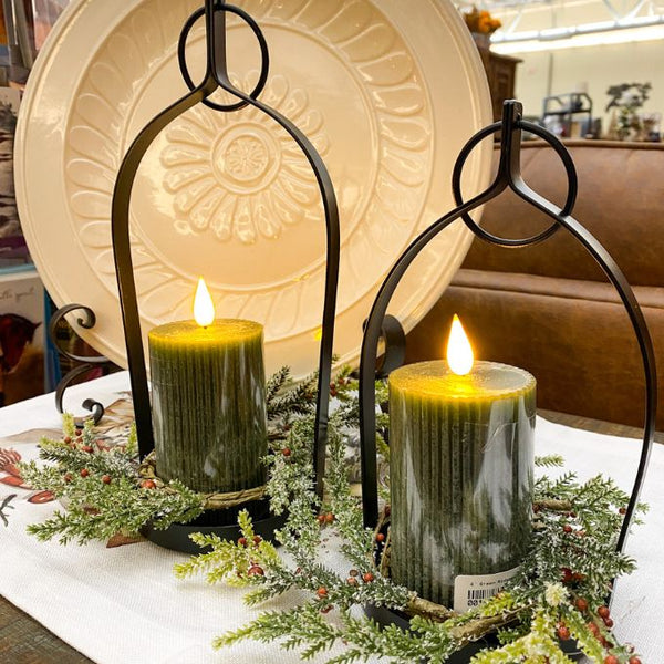 Two lit candles in decorative holders with greenery on a table. Black Metal Open Lanterns - Set of Two available at Quilted Cabin Home Decor.
