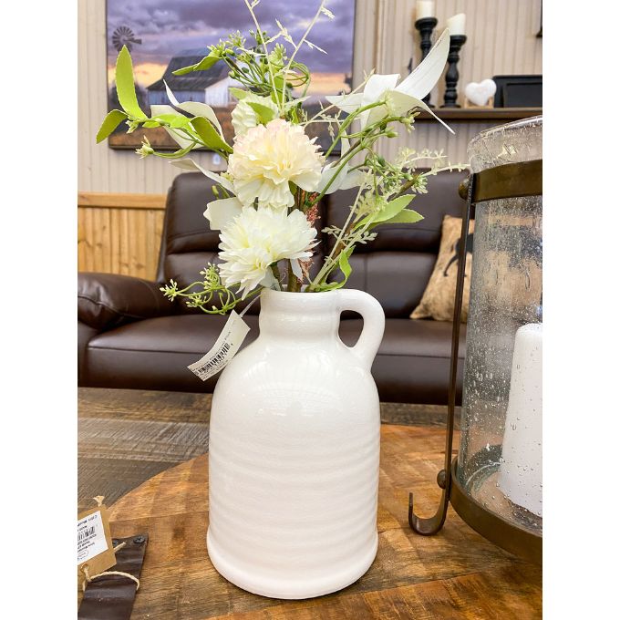 White ceramic vase with flowers on a wooden table in a home setting. White Porcelain Jug-Style Vase available at Quilted Cabin Home Decor. 