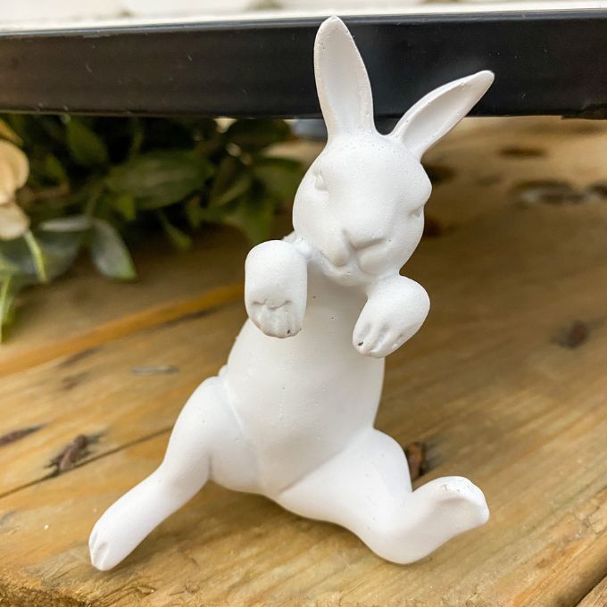 White ceramic rabbit figurine on a wooden surface with a blurred background. Porcelain Bunny Pot Hanger available at Quilted Cabin Home Decor.