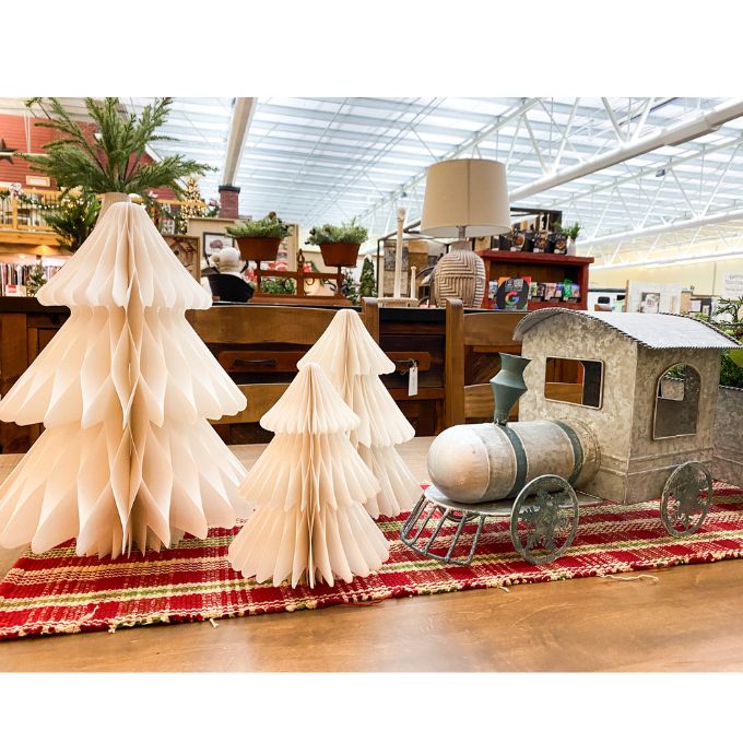 Decorative paper trees and a model train on a red and gold striped rug in a store setting. Vintage White Paper Trees - Three Sizes available at Quilted Cabin Home Decor.