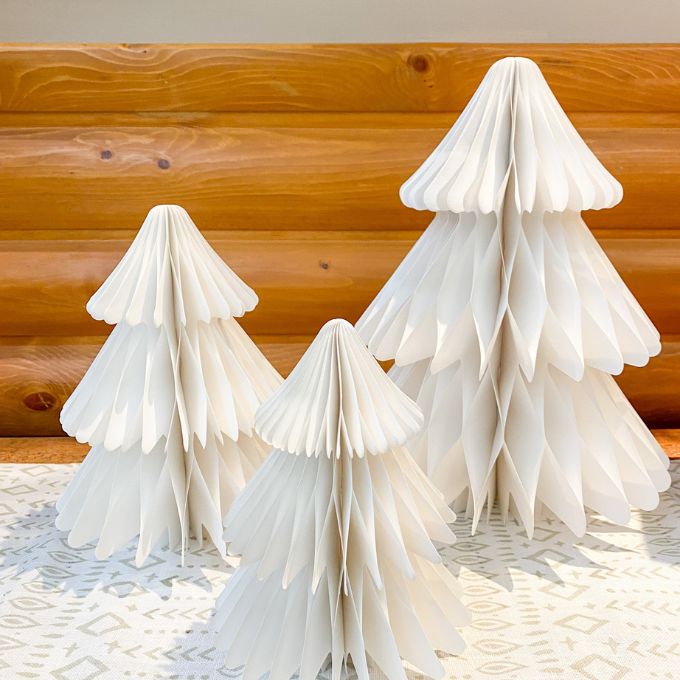 Three white paper trees on a textured surface with a wooden background. Vintage White Paper Trees - Three Sizes available at Quilted Cabin Home Decor.