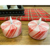 Two red and white striped candles on a wooden surface with a plaid cloth in the background. Short Peppermint Votive LED Timer Candles - Set of Two available at Quilted Cabin Home Decor.