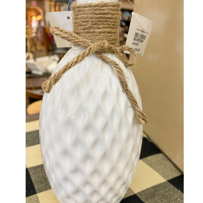 Decorative white bottle with textured surface and jute bow on a checkered table runner. Porcelain Textured Vase available at Quilted Cabin Home Decor.
