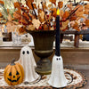 Halloween-themed tabletop decor set featuring a carved orange jack-o'-lantern, a white ghost figurine, a black pillar candle with a white ghost base, and a large bronze urn filled with autumn leaves and berries. Available at Quilted Cabin in Airdrie