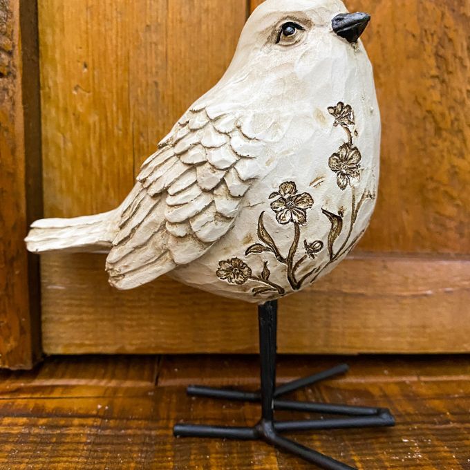 Decorative bird figurine with floral patterns against a wooden background. Engraved Floral Bird Figurine available at Quilted Cabin Home Decor.