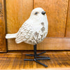 Decorative white bird figurine with floral patterns against a wooden background. Engraved Floral Bird Figurine available at Quilted Cabin Home Decor.